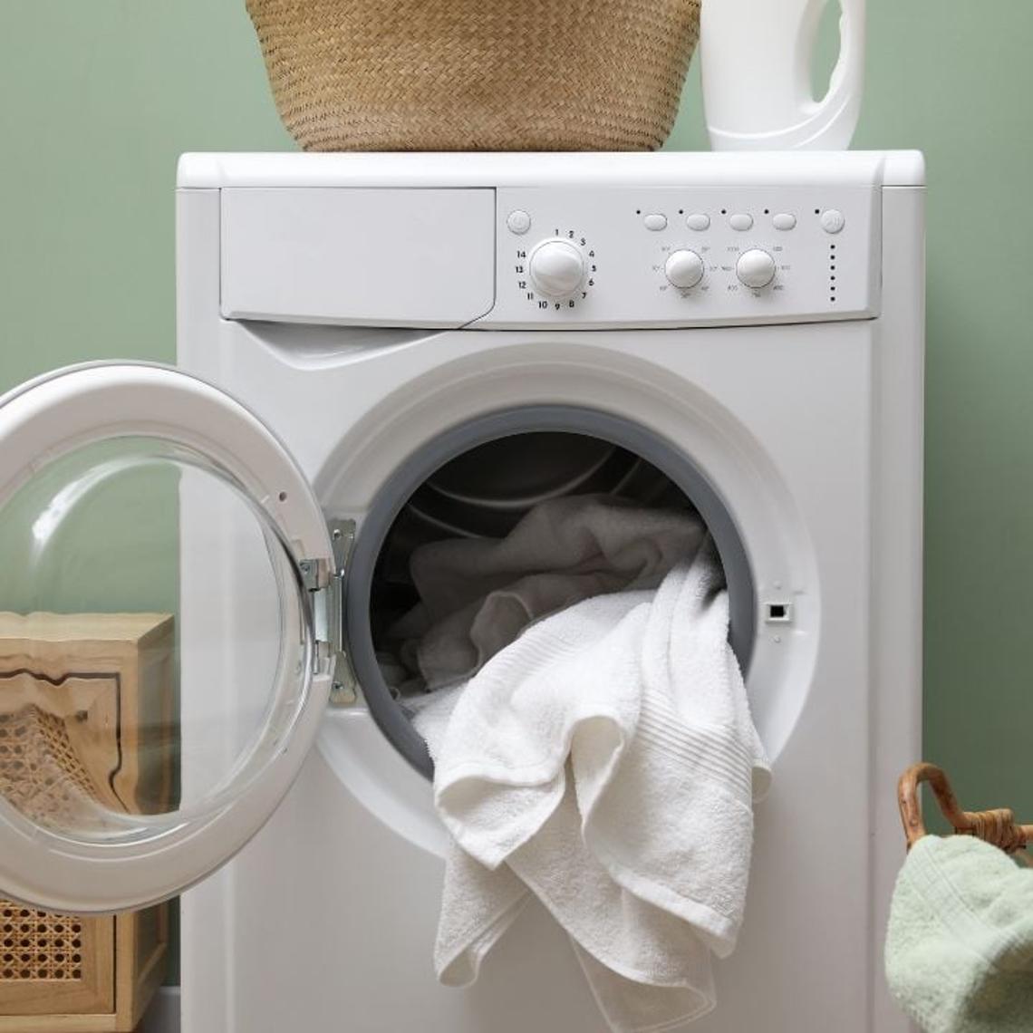Washing machine with the door open and a towel inside.