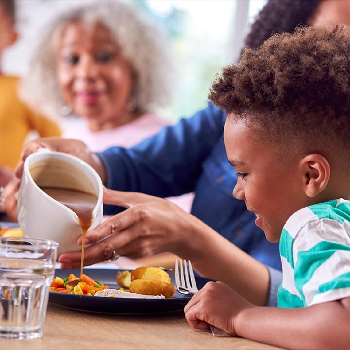 Child pouring gravy on his dinner
