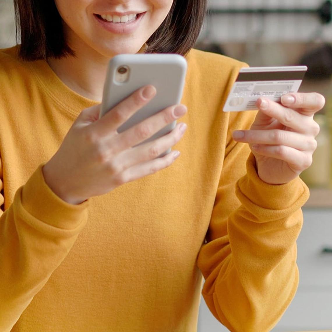 Woman paying bill with mobile phone in hand