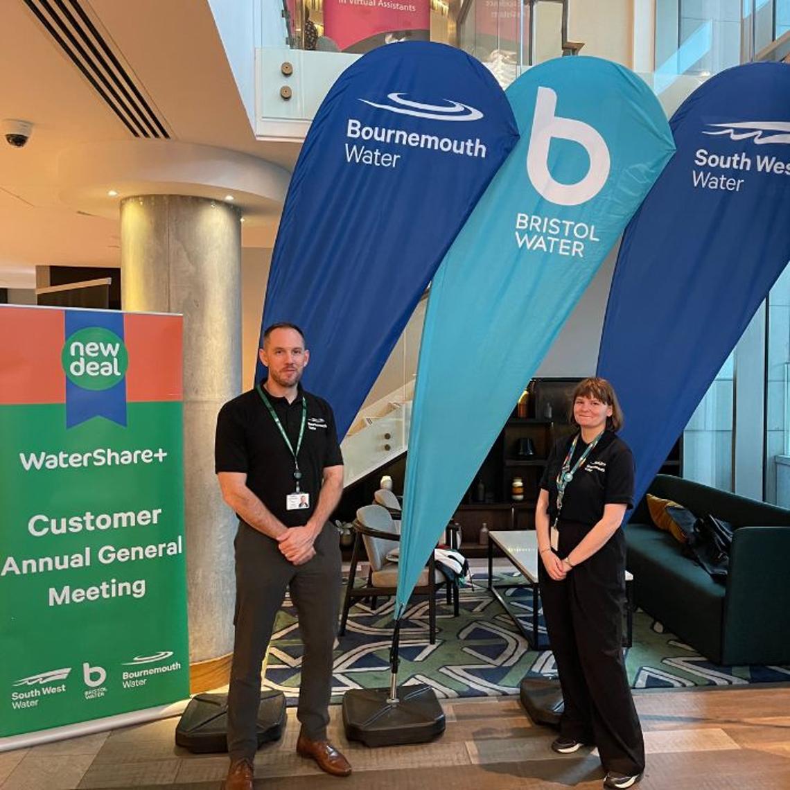 man and a woman stood in front of pan branded flags next to a roller banner sign