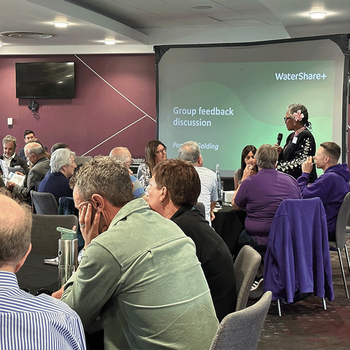 lady stood with microphone presenting in a meeting