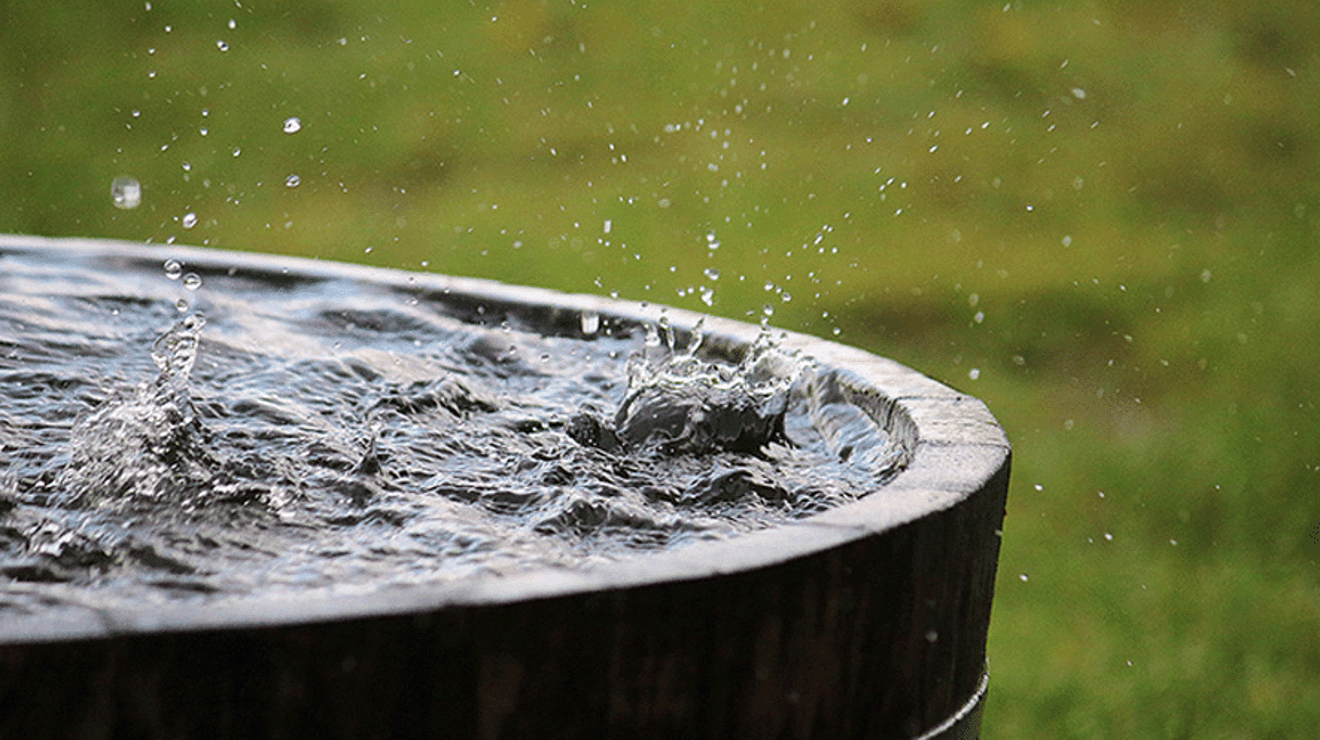 Photo of rain splashing in wooden bucket