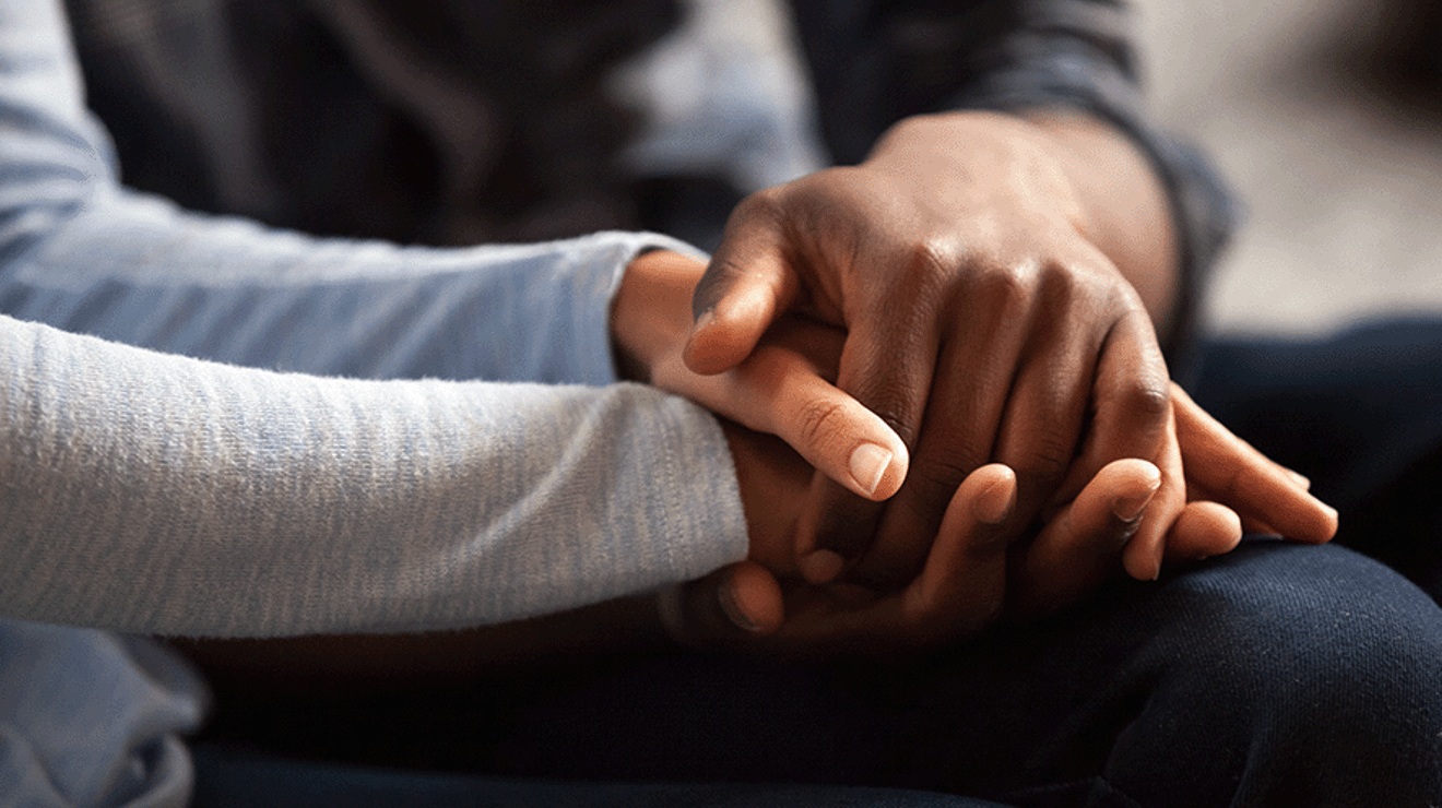 Two people holding hands in support 