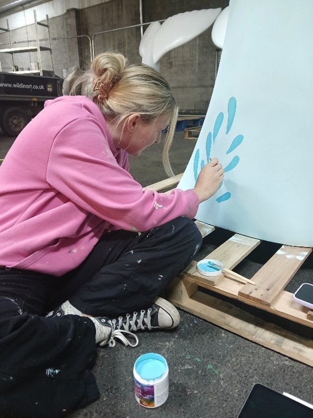 Becky the artist painting a mermaid tail in a blue pattern